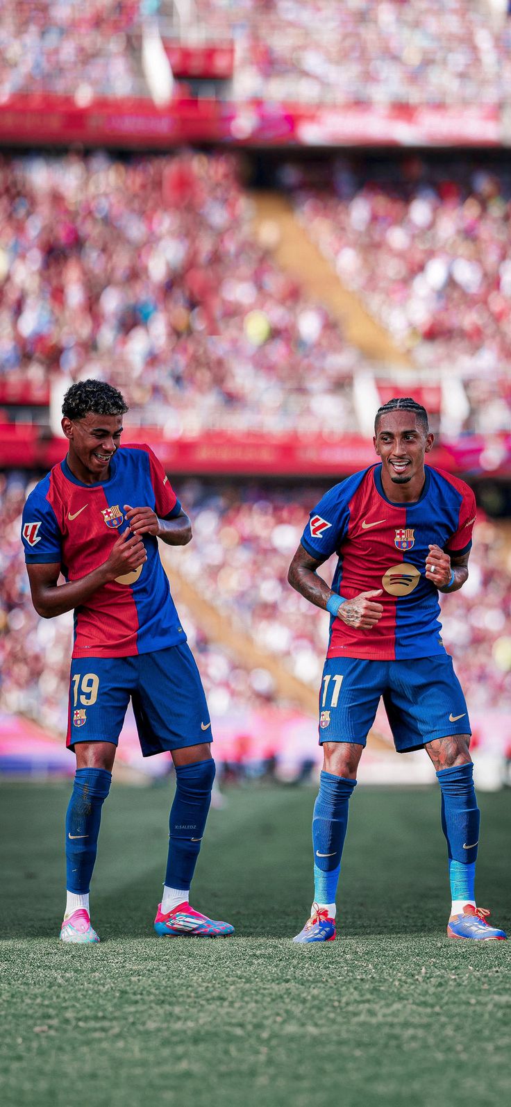 two soccer players standing next to each other in front of a stadium full of people