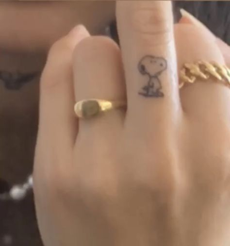 a person wearing a ring with a small snoopy dog on it's finger