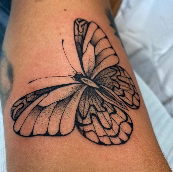 a black and white butterfly tattoo on the leg