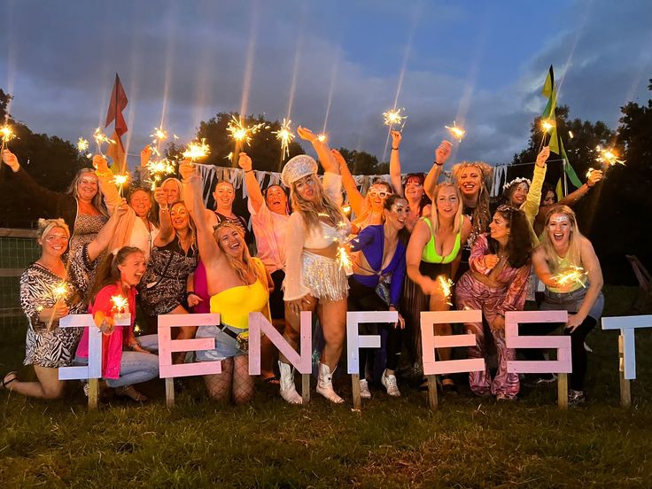 a group of people holding up sparklers in front of a sign that says denfest