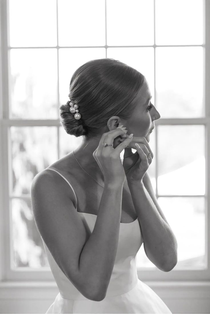 a woman in a wedding dress is talking on her cell phone while looking out the window