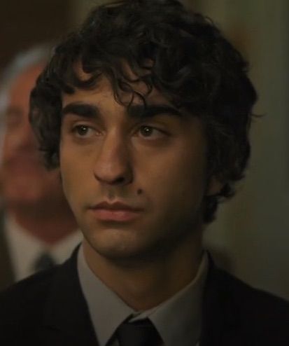 a man with curly hair wearing a suit and tie