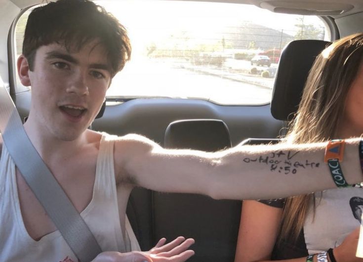 two people sitting in the back seat of a car with tattoos on their arm and wrist