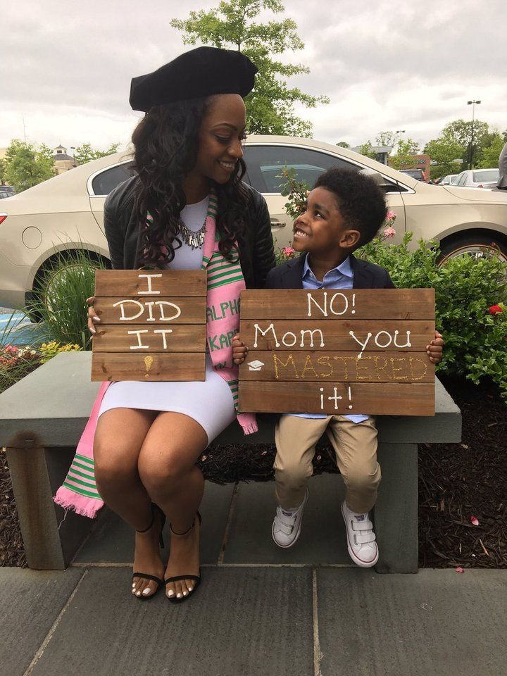 a woman sitting on top of a bench next to a little boy holding a sign