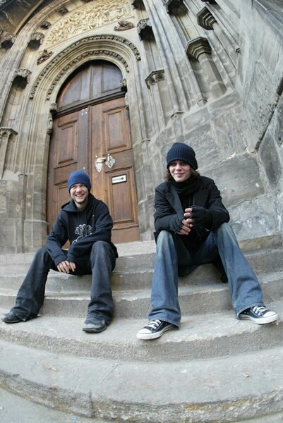 two young men sitting on steps in front of a door