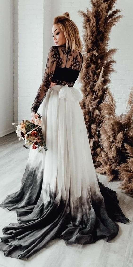 a woman in a black and white dress standing next to a christmas tree with flowers