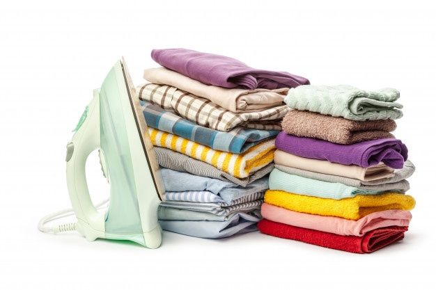 a stack of folded towels next to an iron