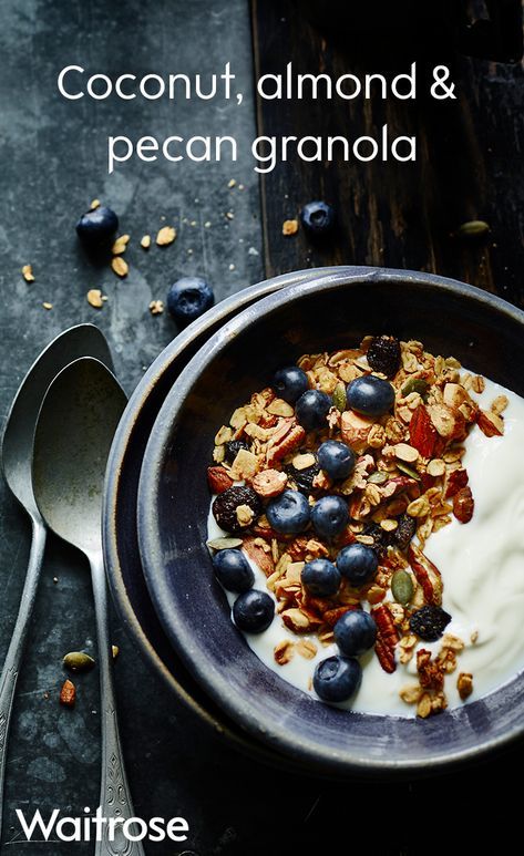 a bowl filled with granola, blueberries and yogurt next to a spoon