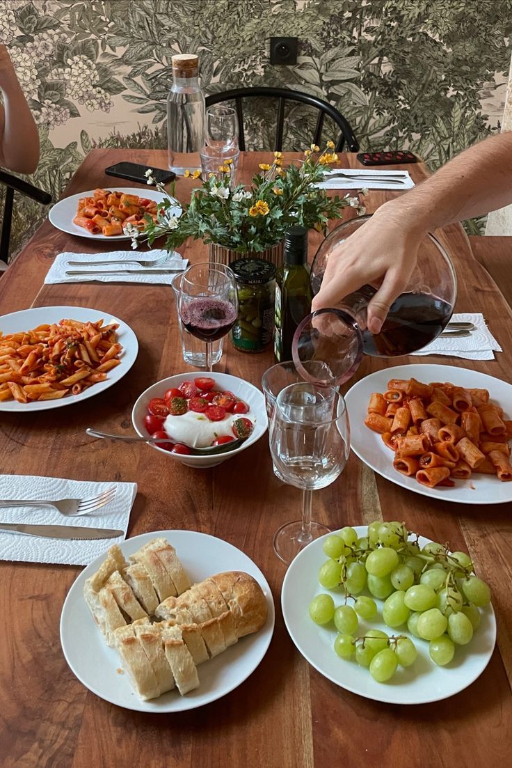 a table topped with plates of food next to wine glasses and utensils on top of a wooden table