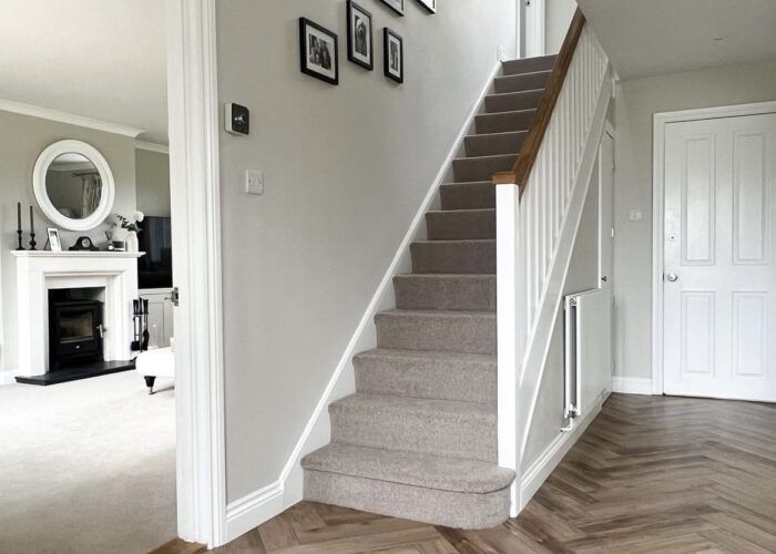 a staircase leading up to a living room with pictures on the wall and wood flooring