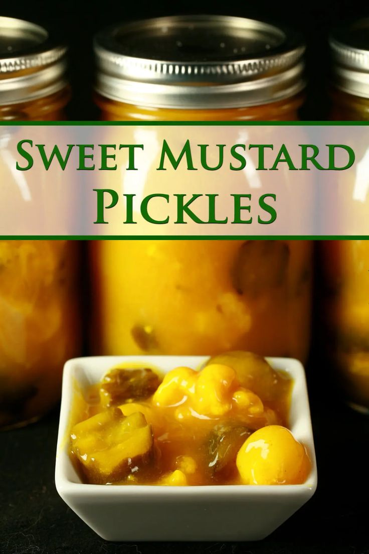 sweet mustard pickles in a white bowl on a black table with jars behind them