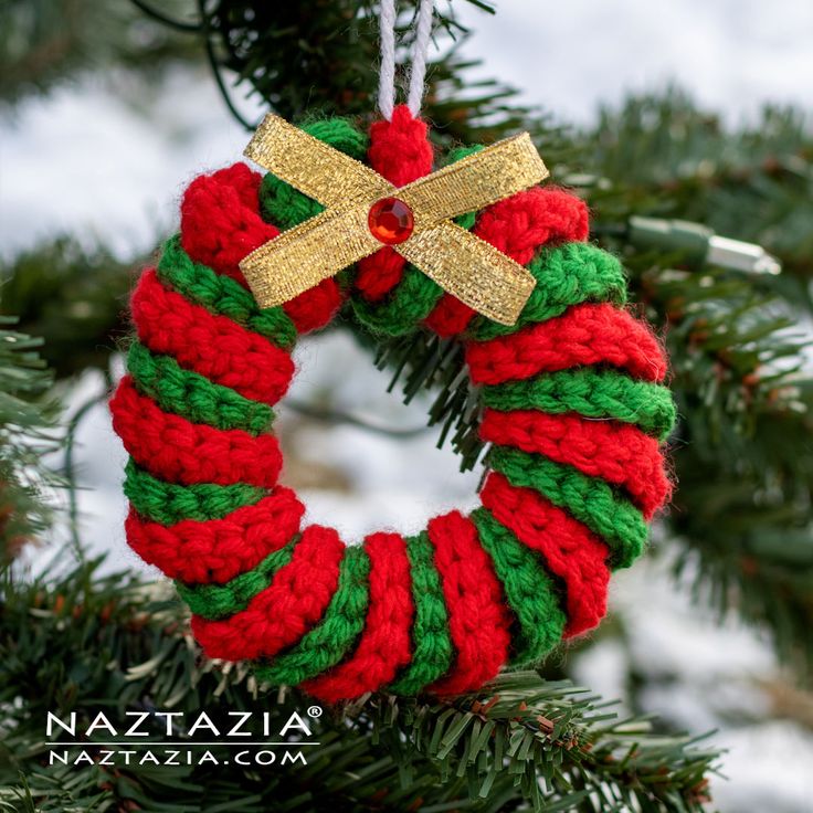 a crocheted christmas wreath hanging from a tree with gold ribbon and bow on it