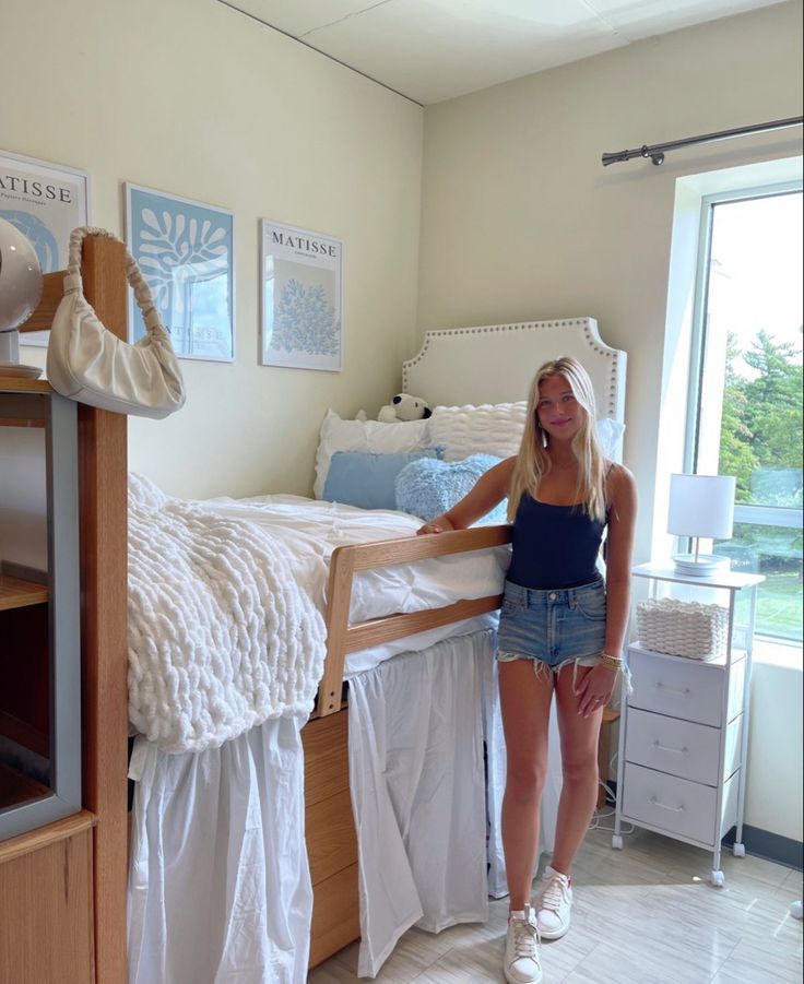 a woman standing next to a bed in a bedroom