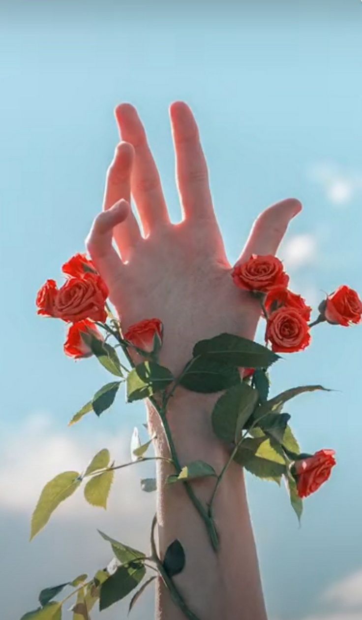 a person's hand reaching up into the air with roses on it