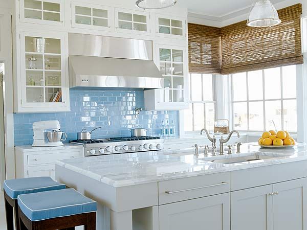 a kitchen with white cabinets and blue backsplash