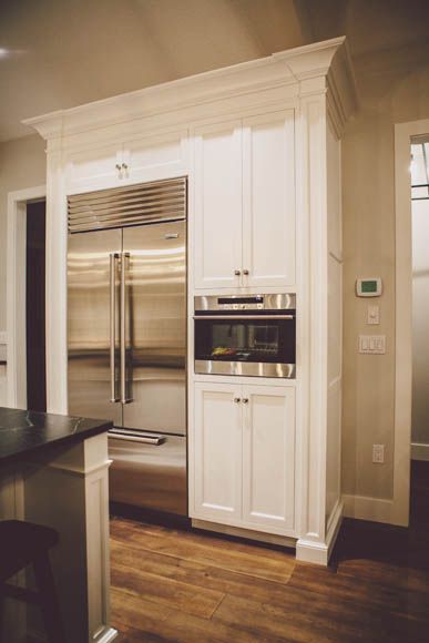 a kitchen with white cabinets and stainless steel refrigerator freezer next to an island in the middle