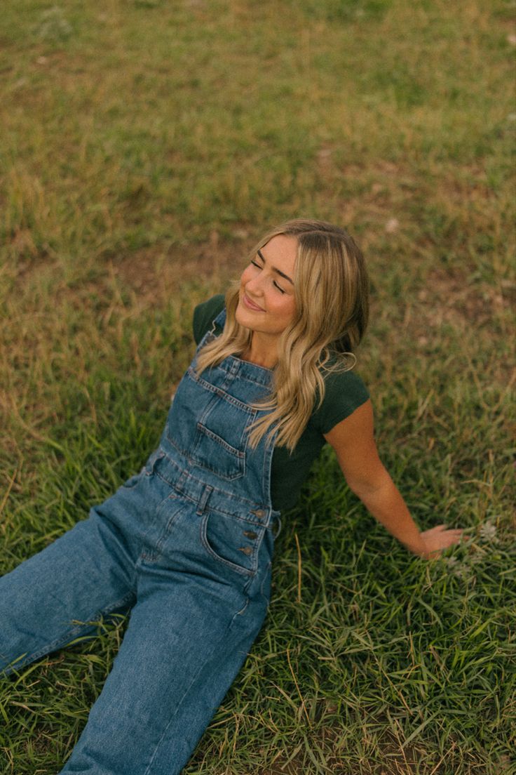 a woman laying on the ground in overalls