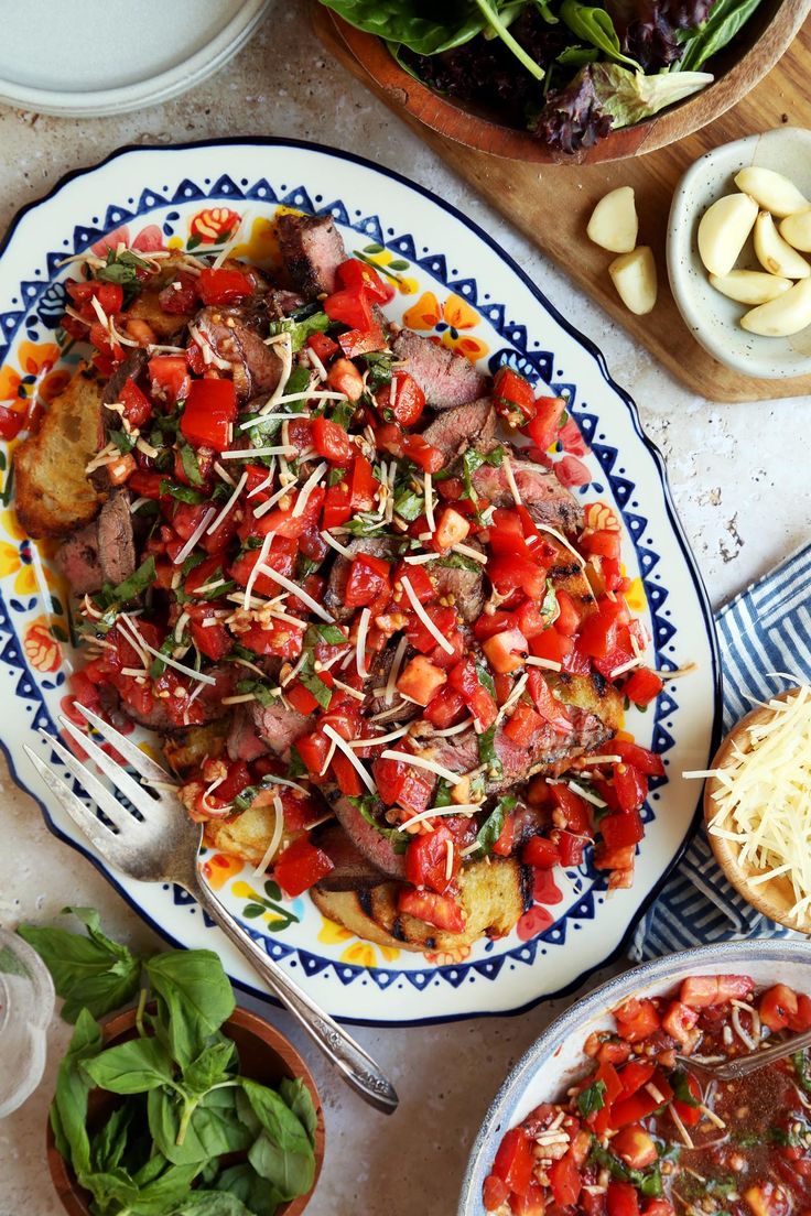 a table topped with plates of food and bowls of salad on top of each other