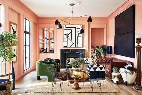 a living room filled with lots of furniture next to a fire place in a pink wall