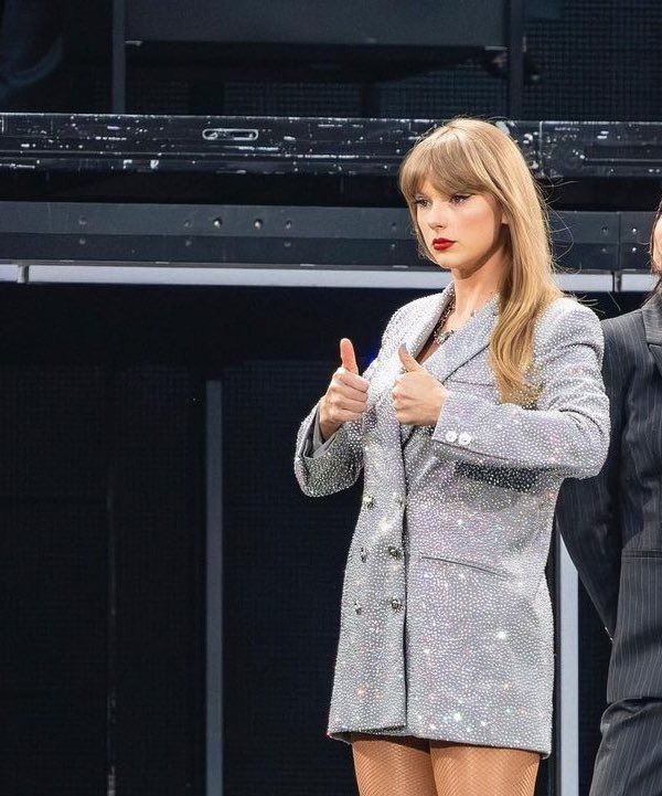 two people standing next to each other in front of a stage with one person giving the thumbs up