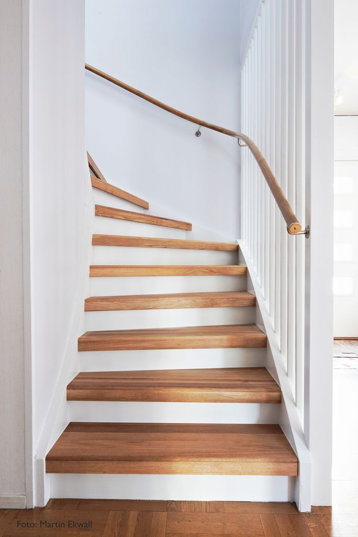 a wooden staircase with white railing and handrails in a home's entryway