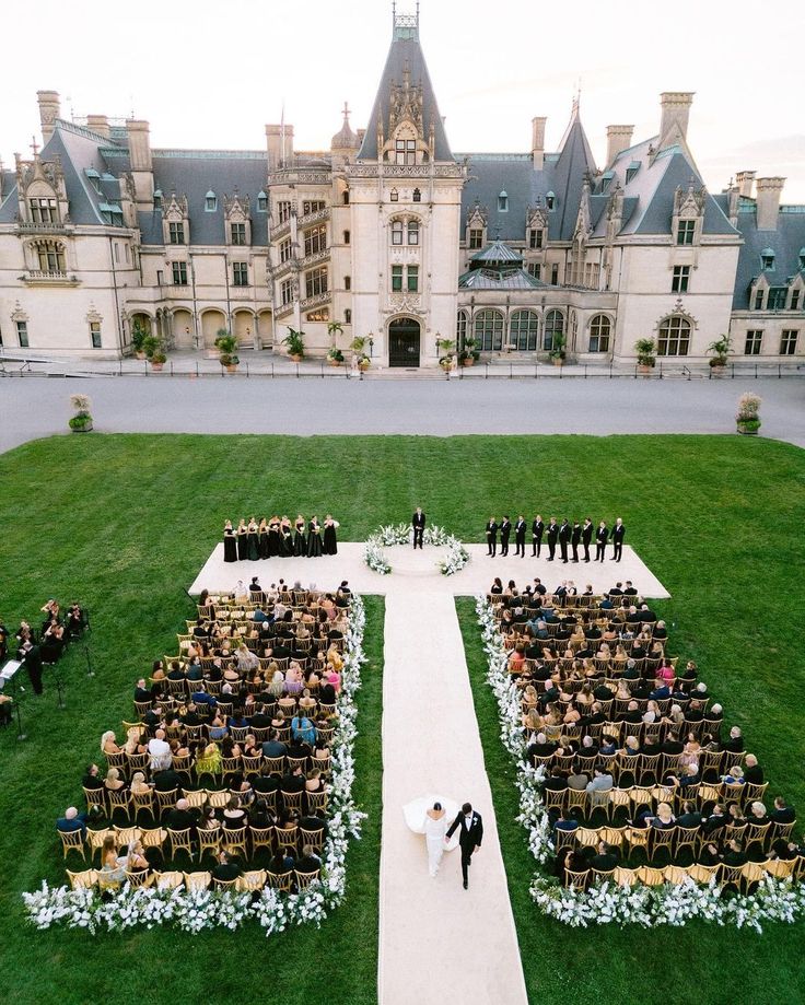 an aerial view of a wedding ceremony in front of a castle