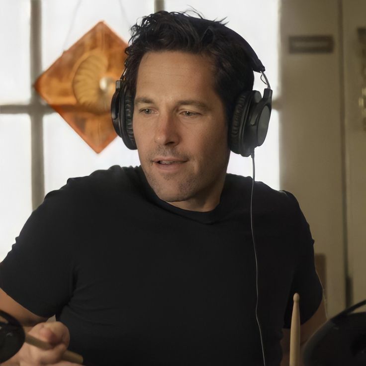 a man wearing headphones sitting in front of a drum kit and looking at the camera