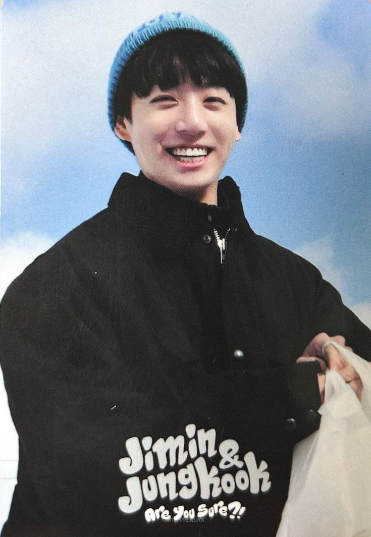 a young man with a blue hat and black jacket is holding a white paper bag