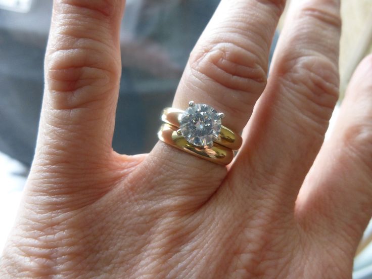 a close up of a person's hand with a diamond ring on their finger