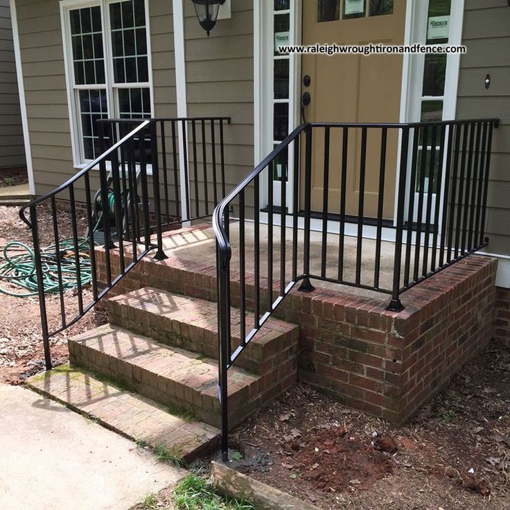 a black iron stair rail next to a brick step leading up to a front door