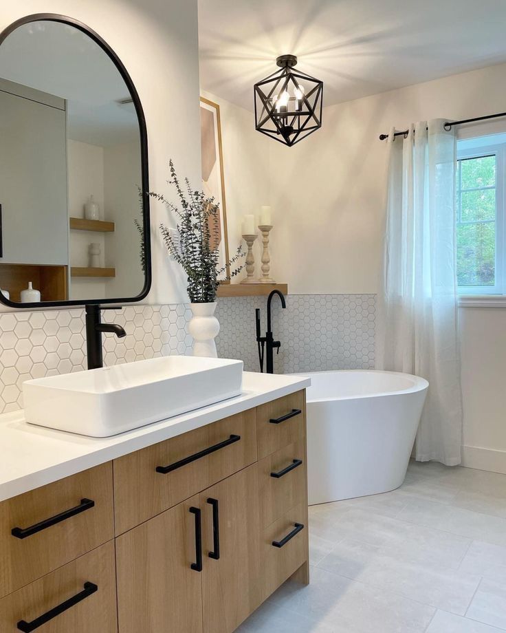 a bathroom with a large white tub next to a sink and a mirror on the wall