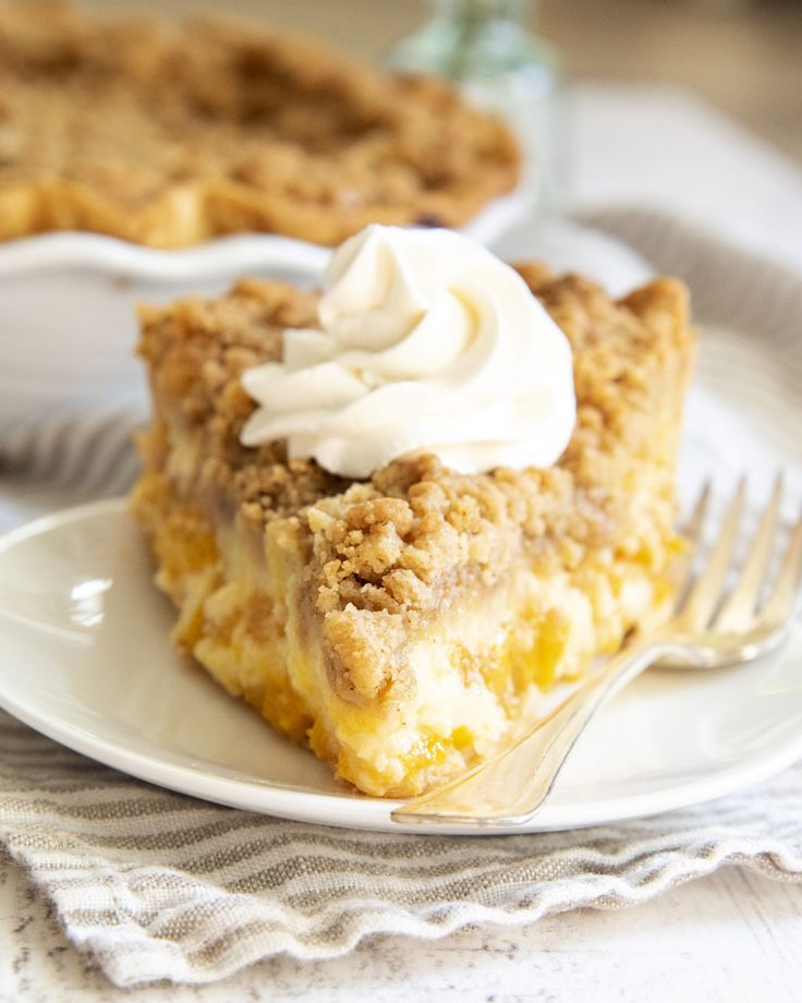 a piece of pie on a white plate with a fork next to it and another pie in the background