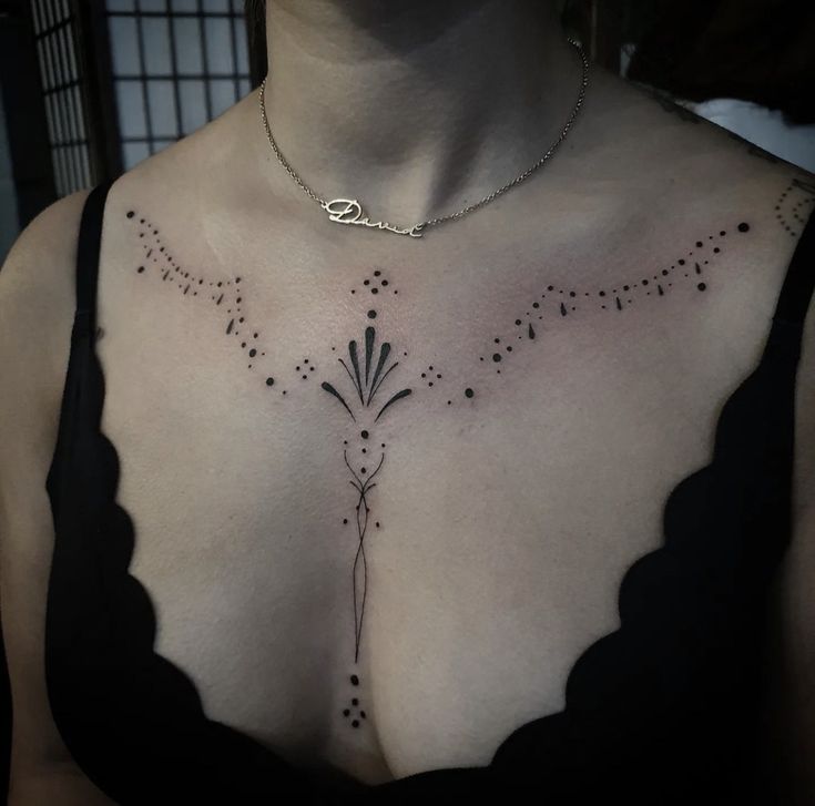 a woman's chest with black dots on it, and a flower design in the middle