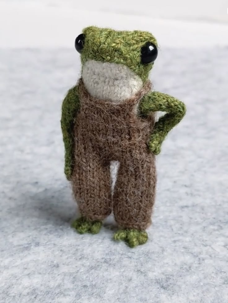 a small stuffed frog is posed on the snow