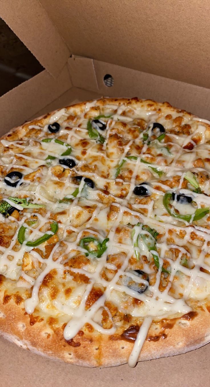 a pizza in a box with cheese and green peppers on it's crusts