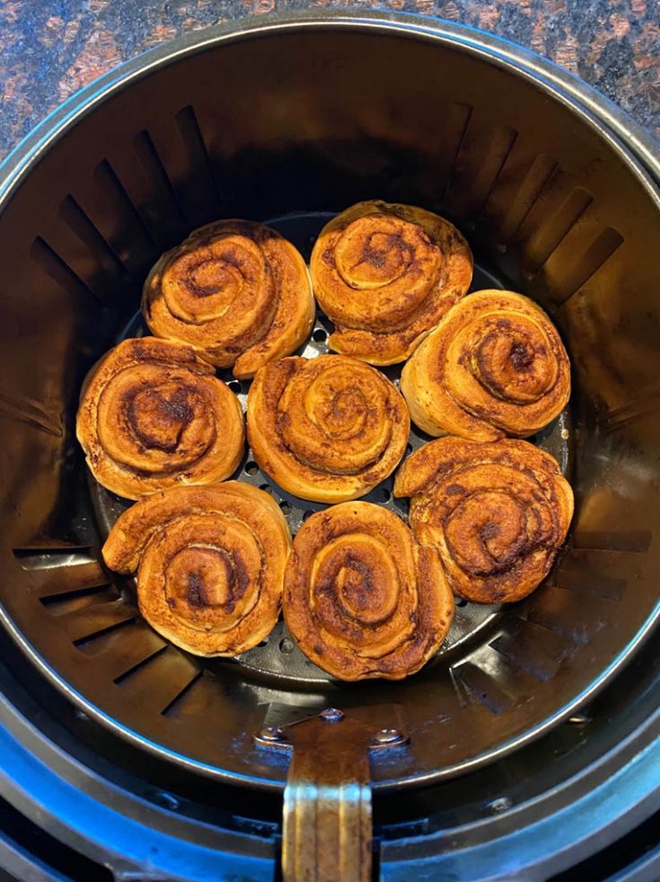 some cinnamon rolls are sitting in the air fryer and ready to be cooked for dinner