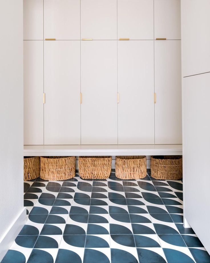 an empty room with white cupboards and black and white floor tiles on the ground