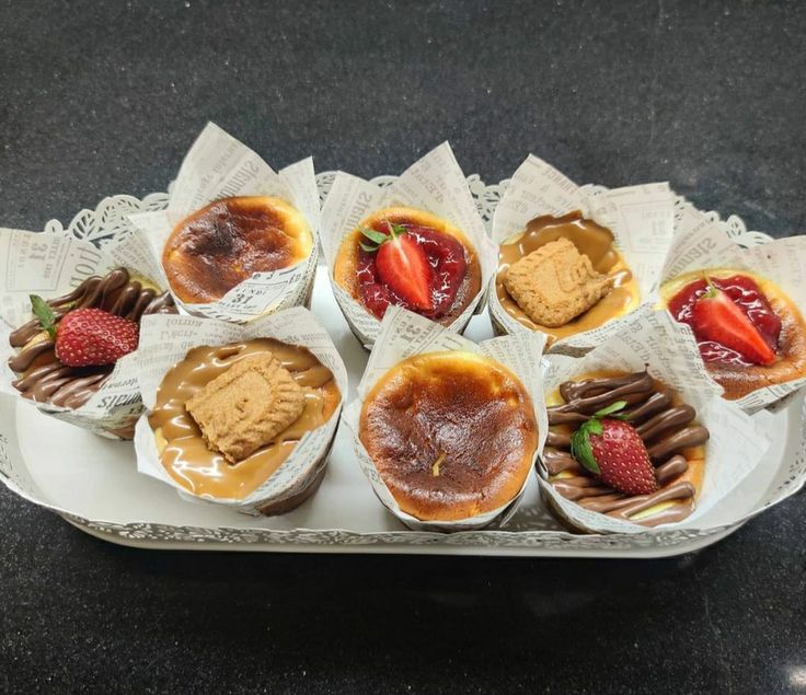 there are many small desserts on the tray with chocolate and strawberries in them