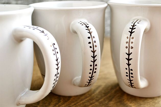 three white coffee mugs with black stitching on them sitting next to each other