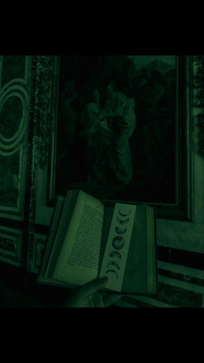 an open book sitting on top of a table in front of a wall with paintings