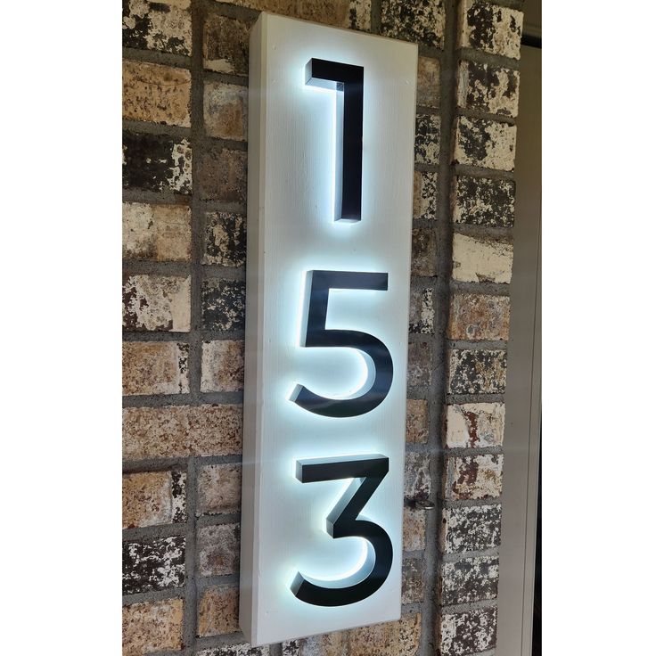 a large illuminated sign with the number twenty five on it's side next to a brick wall