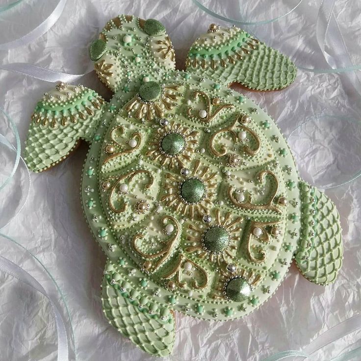 a green beaded turtle sitting on top of a white sheet