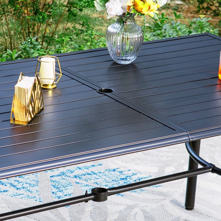 a table with two vases on top of it and some flowers in the background