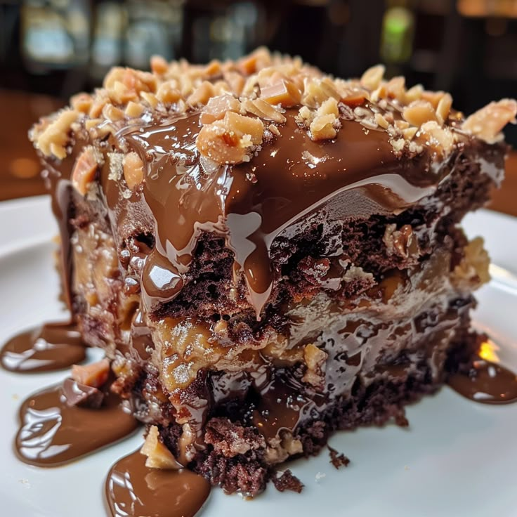 a piece of cake with chocolate frosting and nuts on top is sitting on a white plate