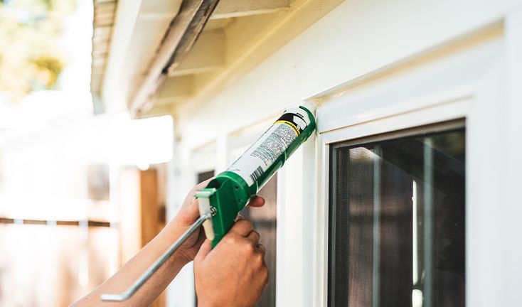 a person is painting the outside of a house with a green paintbrush and glue