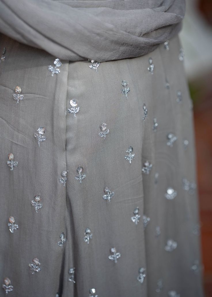 The Innaya Lehenga is a grey monochromatic lehenga set with silver embroidery. This fully embroidered blouse paired with a matching flared skirt makes the most elegant evening/cocktail set! Blouse, skirt, and dupatta included. Festive Silver Dress With Resham Embroidery, Elegant Hand Embellished Maxi Lehenga, Elegant Maxi Length Hand Embellished Lehenga, Designer Silver Salwar Kameez With Resham Embroidery, Silver Salwar Kameez With Resham Embroidery, Hand Embellished Silver Party Dress, Silver Embellished Anarkali Set For Festive Occasions, Traditional Silver Designer Dresses, Silver Floor-length Dresses With Resham Embroidery