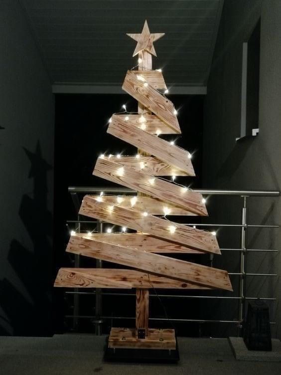 a christmas tree made out of wooden planks with lights around it and an arrow on top