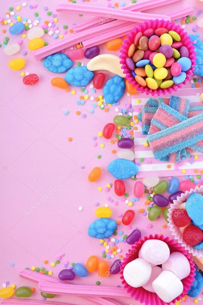 colorful candies and candy on pink background with space for text