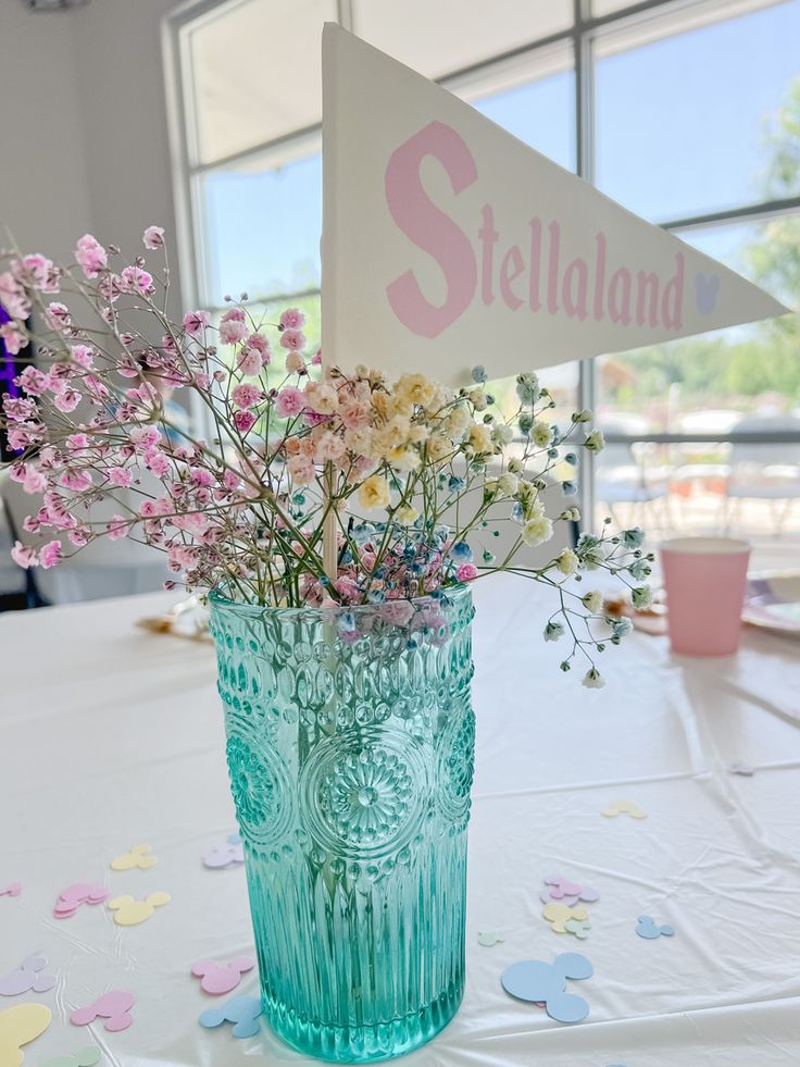 a vase filled with flowers on top of a table next to a sign that says stelland