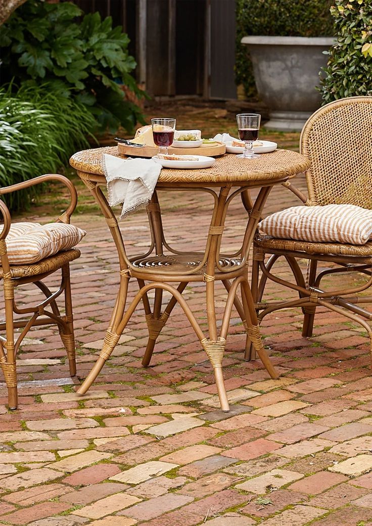 an outdoor table with two chairs and a plate on it in the middle of a brick patio